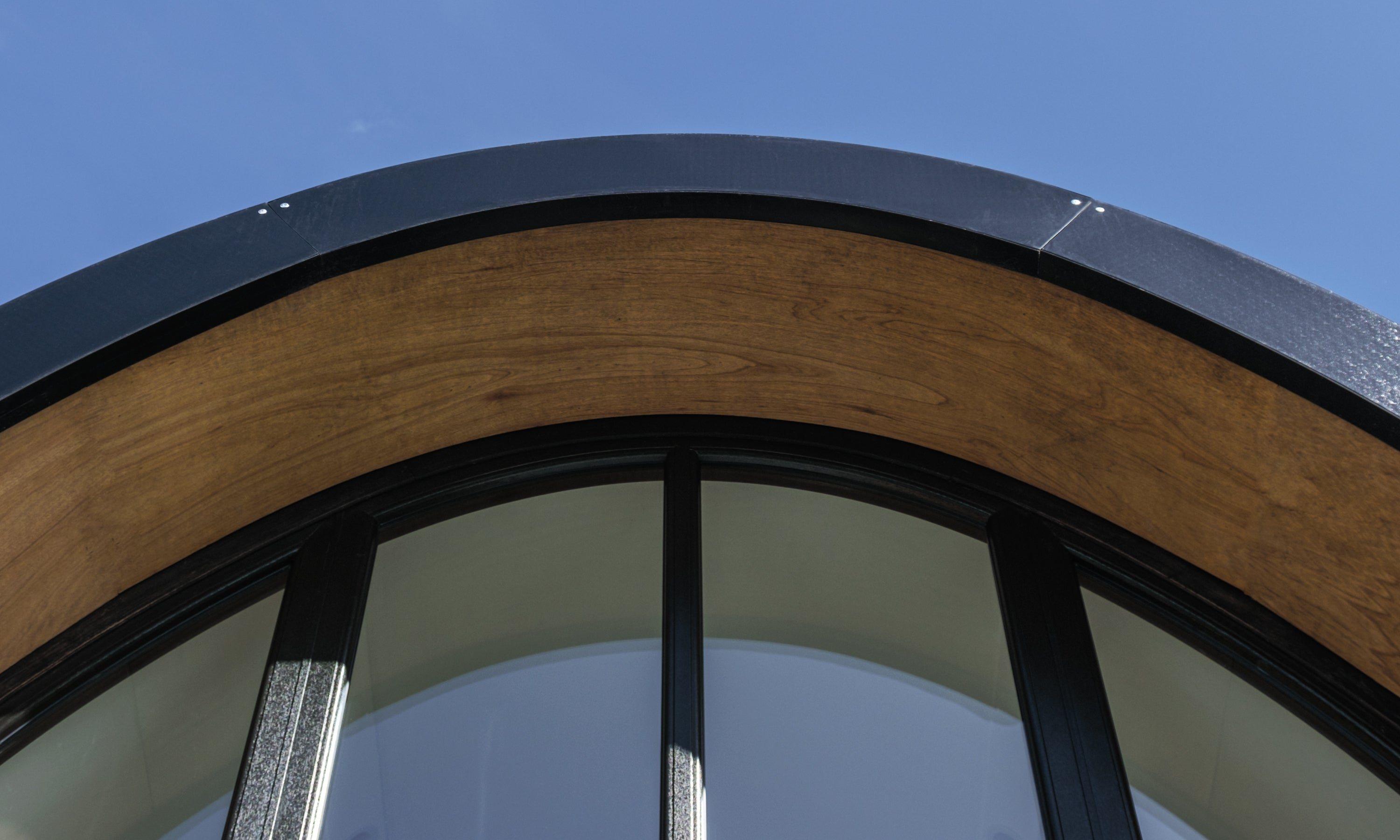 A detail of the curving roof and tall arch window of the prefabricated timber Aviator Lodge modular home in Ireland. 