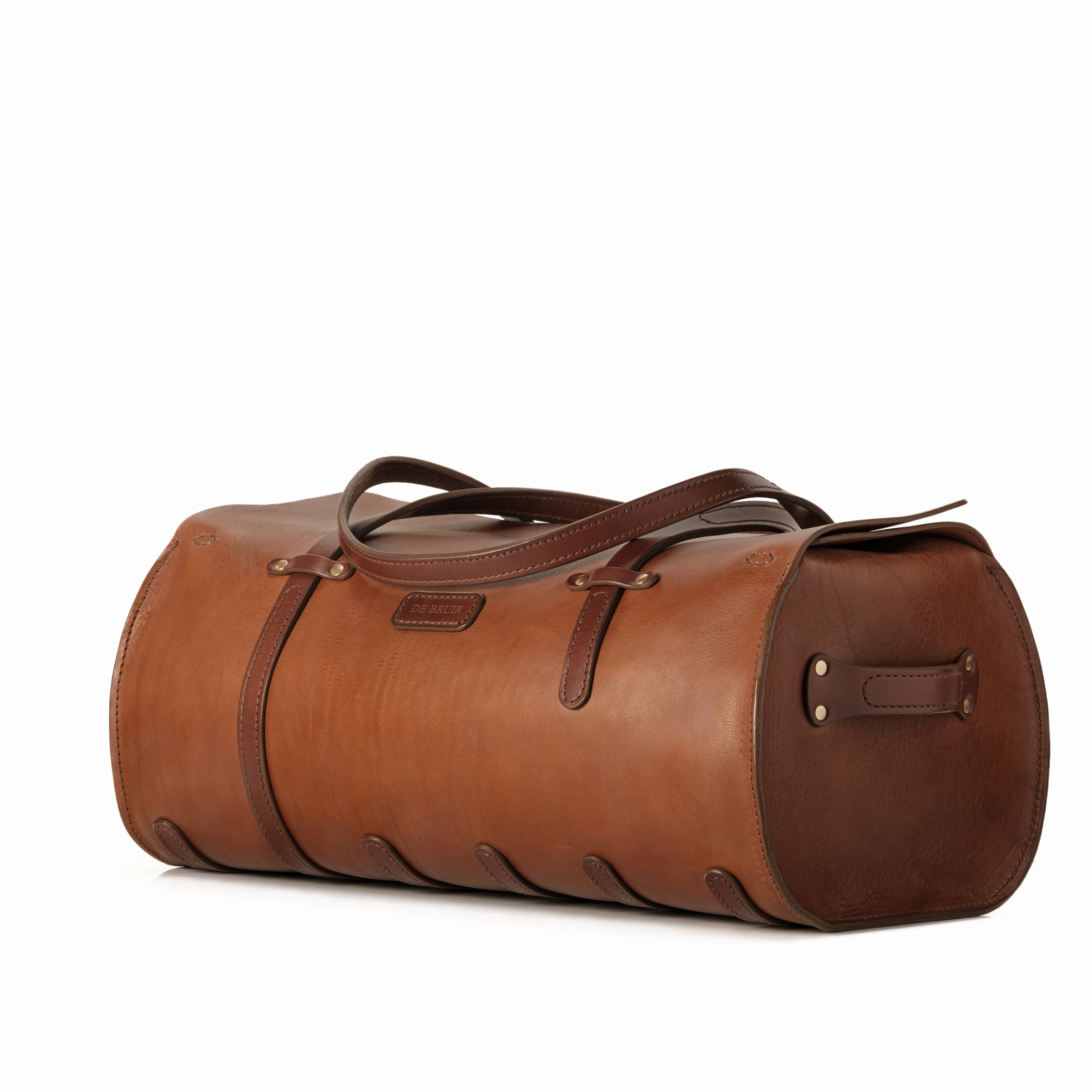 A brown leather duffel bag in a vintage tubular shape made from a large wrap of premium bridle leather. 
The veg-tanned character leather is cut and stitched at the Atelier in Ireland to create this contemporary carrier with an original design style. 
