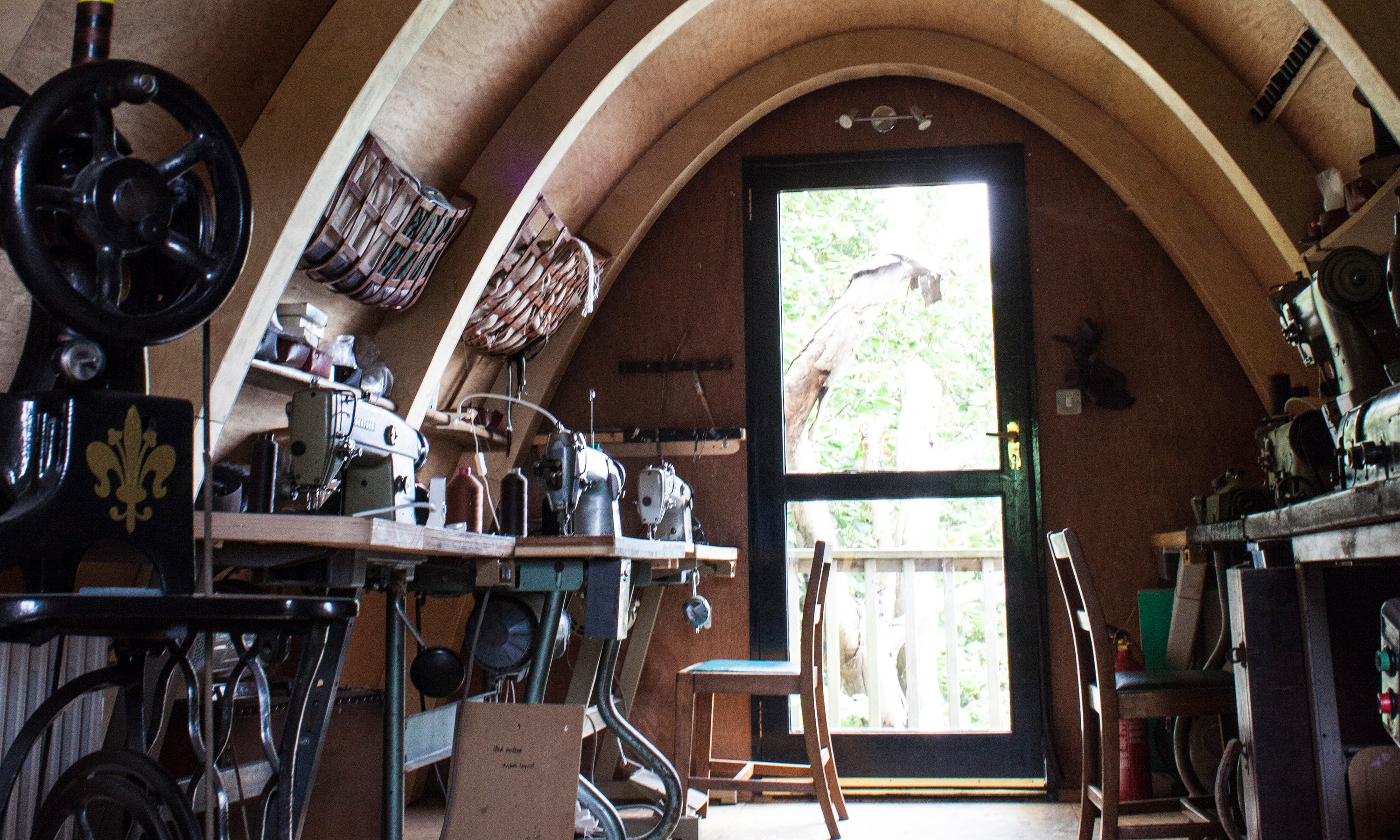 Detail from the jacket-making space at Garvan de Bruir Atelier. There are a collection of Brother and Singer industrial sewing machines. The curved building is a prototype for his Aviator Haus concept. 