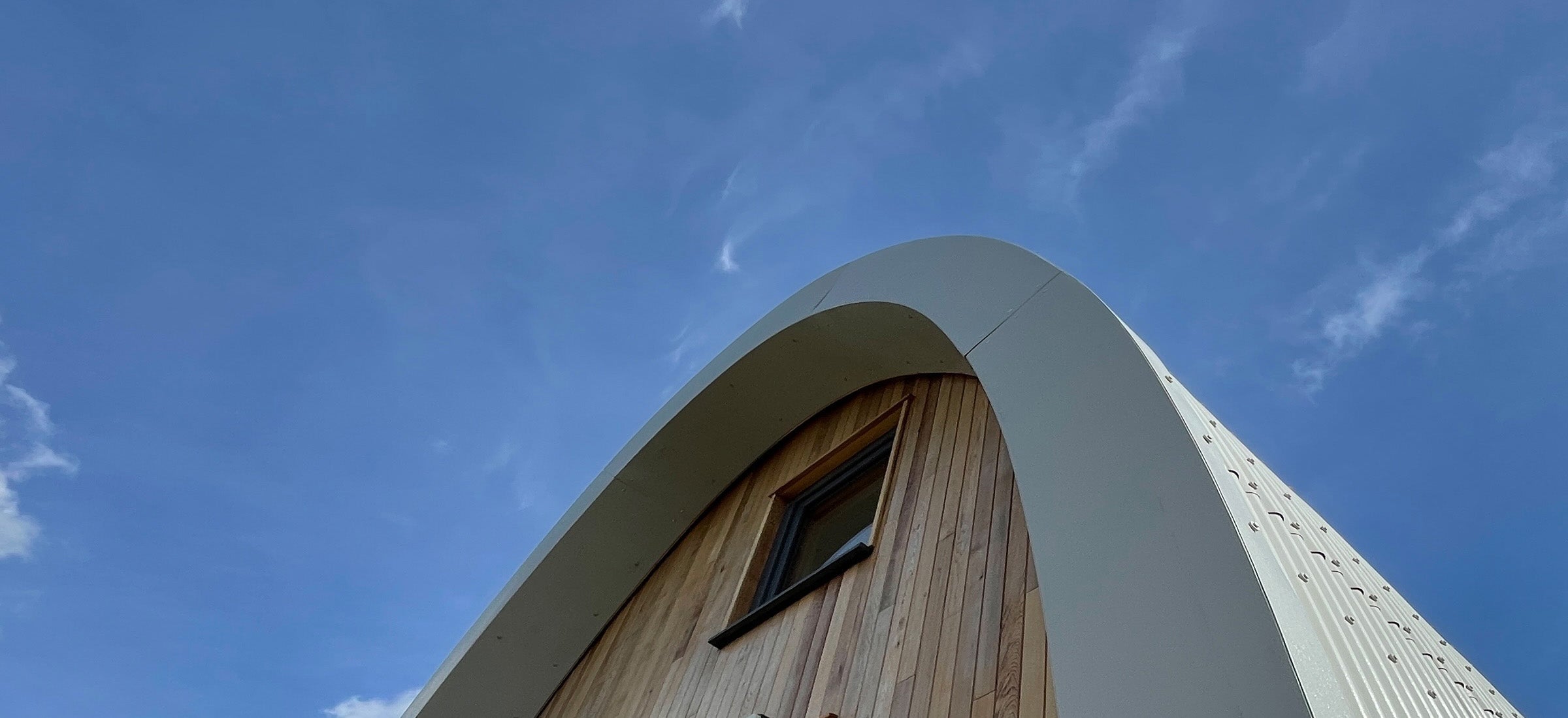 A detail of the cedar clad end wall of the Aviation House and the curving corrugated steel roof and flashing. 