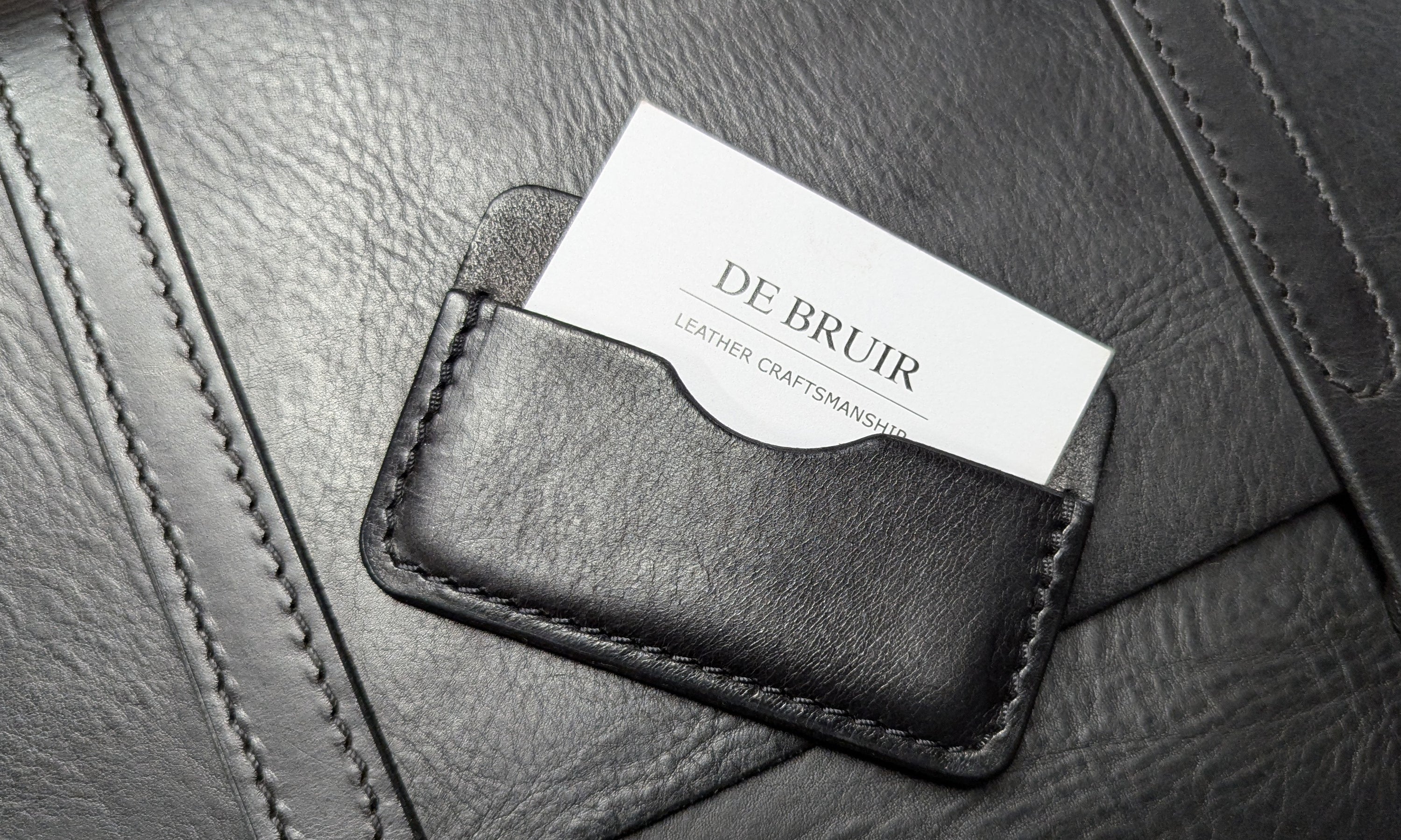 Black leather cover for business cards. Displaying the DE BRUIR contact card