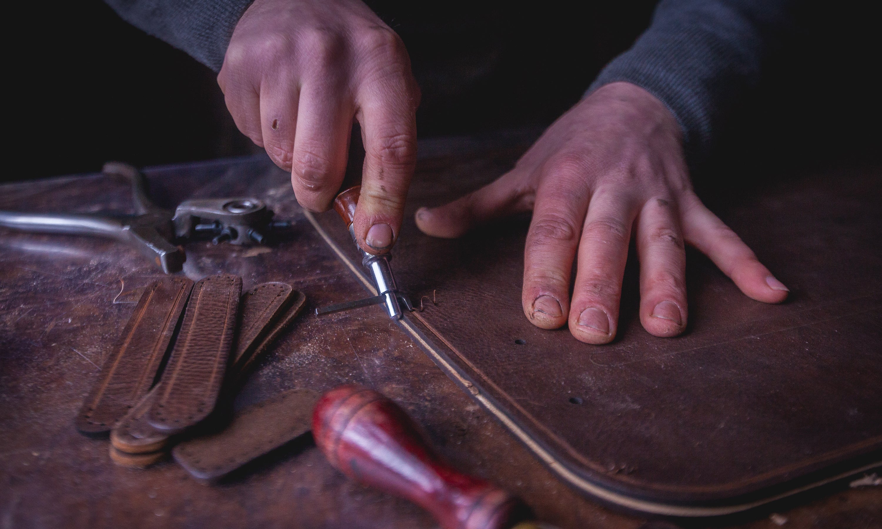 Garvan de Bruir scoring the stitch line into a portion of leather with a hand tool. 